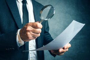 Tax inspector investigating financial documents through magnifyi 533045204 3866x2581 1 1024x684