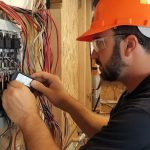 A licensed commercial electrician installing new energy-efficient LED lighting in a modern office renovation project.