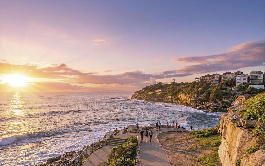 Early morning Bondi to Coogee coastal walk in Sydney showing pastel sunrise skies, headlands and calm ocean.
